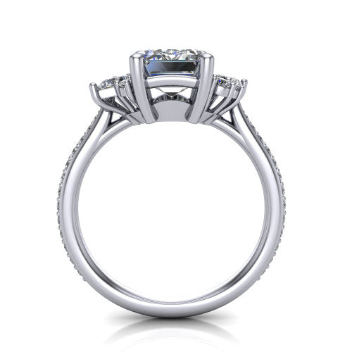 Mila emerald three stone engagement ring in 18K White Gold, through-finger front profile showing the center head raised above the round accent clusters and pav&eacute; band