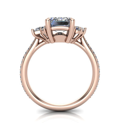 Mila emerald three stone engagement ring in 18K Rose Gold, through-finger front profile showing the center head raised above the round accent clusters and pav&eacute; band