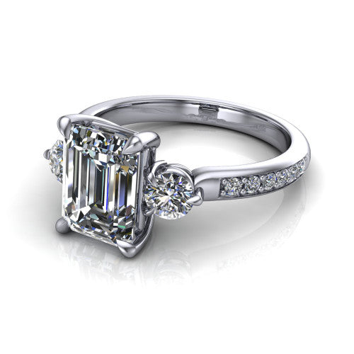 Blake emerald three stone engagement ring in Platinum, three-quarter perspective showing the center diamond between two round side stones above a pav&eacute; shank