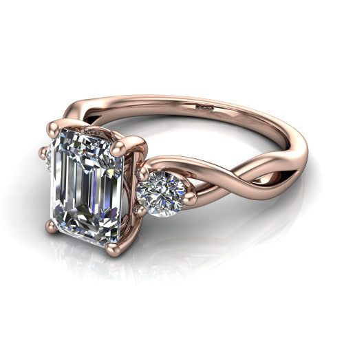 Alina emerald three stone engagement ring in 18K Rose Gold, three-quarter perspective showing the emerald center between two round side stones above a twisted vine band