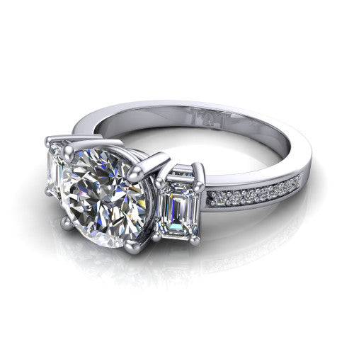 Freya round three stone engagement ring in Platinum, three-quarter perspective showing the round center between two emerald cut side stones above a pav&eacute; band