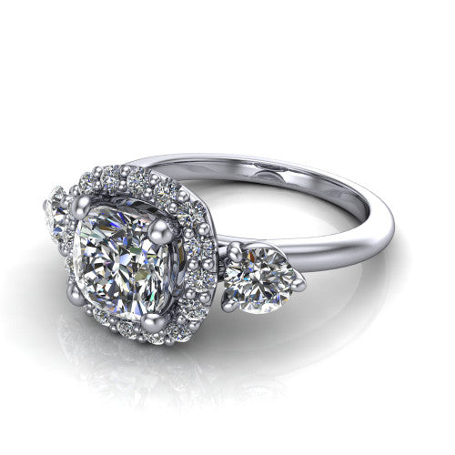 Carol cushion three stone halo engagement ring in 18K White Gold, three-quarter perspective showing the cushion center in a squared pav&eacute; halo flanked by two round side stones above a plain band