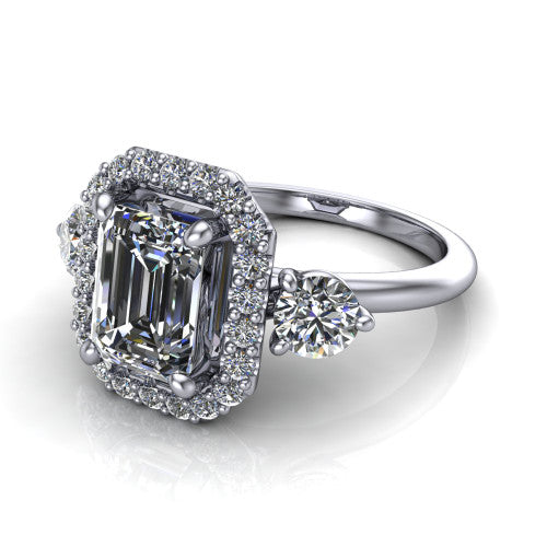 Carol emerald three stone halo engagement ring in Platinum, three-quarter perspective showing the emerald center in a squared pav&eacute; halo flanked by two round side stones above a plain band
