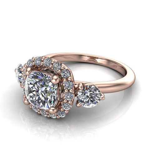 Carol cushion three stone halo engagement ring in 14K Rose Gold, three-quarter perspective showing the cushion center in a squared pav&eacute; halo flanked by two round side stones above a plain band