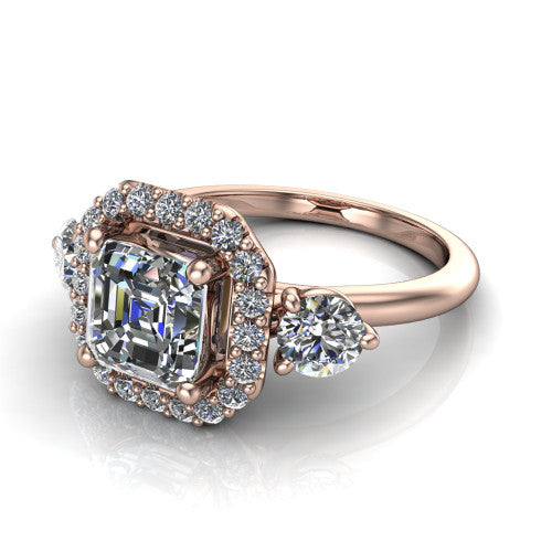 Carol square emerald three stone halo engagement ring in 14K Rose Gold, three-quarter perspective showing the square emerald center in a squared pav&eacute; halo flanked by two round side stones above a plain band