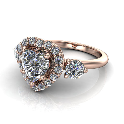 Carol heart three stone halo engagement ring in 14K Rose Gold, three-quarter perspective showing the heart center in a squared pav&eacute; halo flanked by two round side stones above a plain band