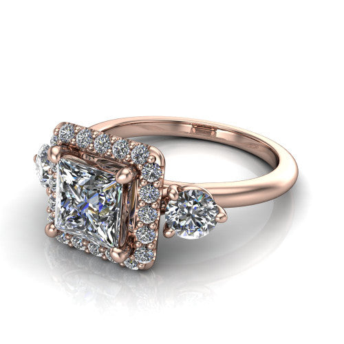 Carol princess three stone halo engagement ring in 14K Rose Gold, three-quarter perspective showing the princess center in a squared pav&eacute; halo flanked by two round side stones above a plain band