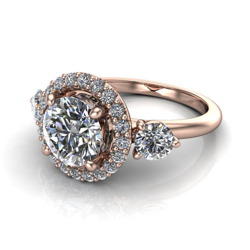 Carol round three stone halo engagement ring in 18K Rose Gold, three-quarter perspective showing the round center in a squared pav&eacute; halo flanked by two round side stones above a plain band