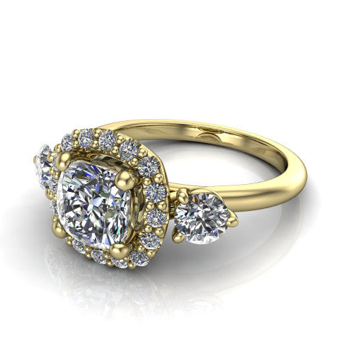 Carol cushion three stone halo engagement ring in 18K Yellow Gold, three-quarter perspective showing the cushion center in a squared pav&eacute; halo flanked by two round side stones above a plain band