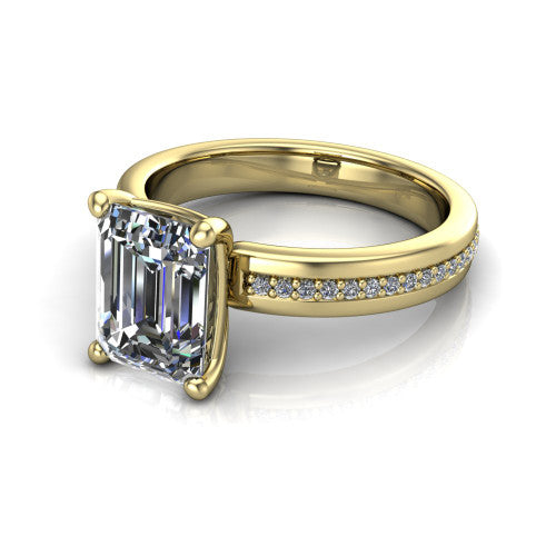 Kamala emerald classic solitaire engagement ring in 18K Yellow Gold, three-quarter perspective showing the emerald center on claw prongs above a wide channel-set pav&eacute; band