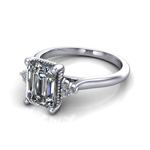Brianna emerald three stone engagement ring in 18K White Gold with milgrain-framed center and round side clusters, three-quarter perspective view
