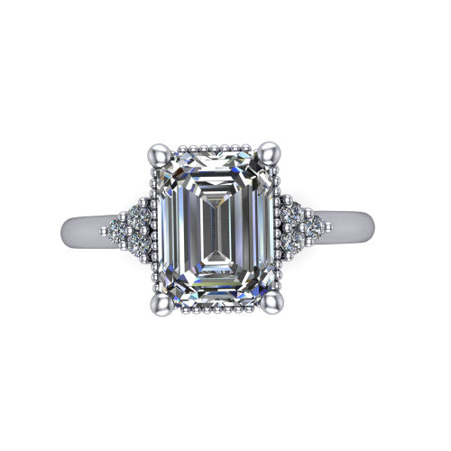 Brianna emerald three stone engagement ring in Platinum with milgrain-framed center and round side clusters, top-down view of the milgrain-framed center and side accent clusters