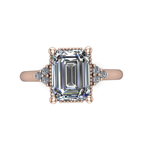 Brianna emerald three stone engagement ring in 18K Rose Gold with milgrain-framed center and round side clusters, top-down view of the milgrain-framed center and side accent clusters
