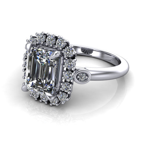 June emerald-cut halo engagement ring in Platinum, three-quarter perspective showing the emerald-cut center diamond in an ornate cluster halo with bezel side accents