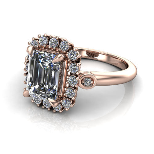 June emerald-cut halo engagement ring in 18K Rose Gold, three-quarter perspective showing the emerald-cut center diamond in an ornate cluster halo with bezel side accents