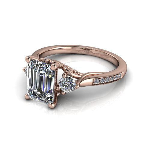 Celine emerald three stone engagement ring in 18K Rose Gold, three-quarter perspective showing the step-cut emerald center diamond flanked by two round side diamonds on a pave band