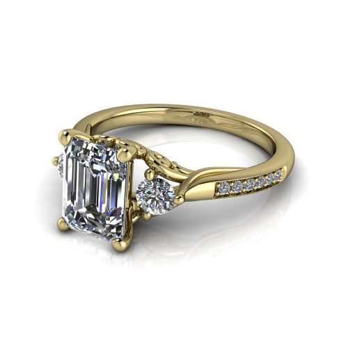 Celine emerald three stone engagement ring in 14K Yellow Gold, three-quarter perspective showing the step-cut emerald center diamond flanked by two round side diamonds on a pave band