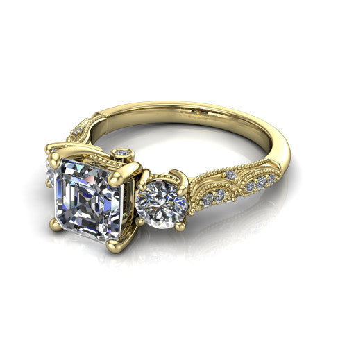 Rosemary square emerald three stone engagement ring in 18K Yellow Gold, three-quarter perspective showing the three-stone row with milgrain shoulders and filigree detailing above a pav&eacute; band