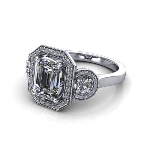 Colette emerald-cut three-stone halo engagement ring in 14K White Gold, three-quarter perspective showing the emerald-cut center diamond and two round side stones, each in a pave halo, across the band