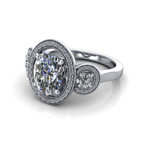 Colette oval three-stone halo engagement ring in 18K White Gold, three-quarter perspective showing the oval center diamond and two round side stones, each in a pave halo, across the band