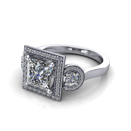 Colette princess-cut three-stone halo engagement ring in 18K White Gold, three-quarter perspective showing the princess-cut center diamond and two round side stones, each in a pave halo, across the band