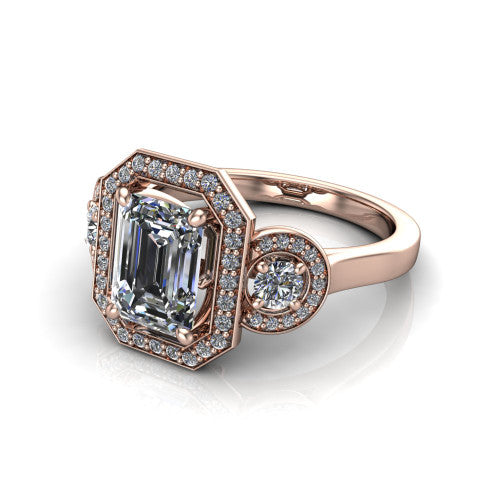 Colette emerald-cut three-stone halo engagement ring in 14K Rose Gold, three-quarter perspective showing the emerald-cut center diamond and two round side stones, each in a pave halo, across the band