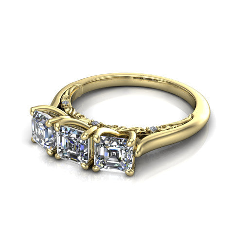 Kora square emerald-cut three-stone engagement ring in 14K Yellow Gold, three-quarter perspective showing the three matched square emerald-cut diamonds, pave-set band, and vintage scrollwork gallery