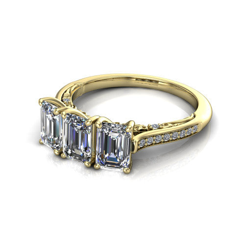 Emory emerald-cut three-stone engagement ring in 18K Yellow Gold, three-quarter perspective showing the three matched emerald-cut diamonds, pave-set band, and filigree under-gallery