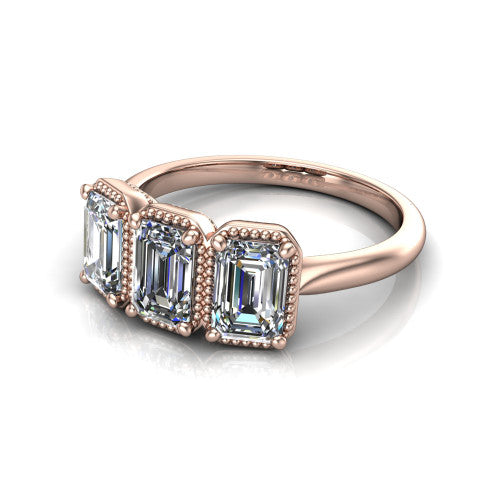 Evangeline emerald-cut three-stone engagement ring in 18K Rose Gold, three-quarter perspective showing three emerald-cut diamonds in milgrain bezels on a polished tapered band
