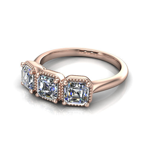 Evangeline square emerald-cut three-stone engagement ring in 18K Rose Gold, three-quarter perspective showing three square emerald-cut diamonds in milgrain bezels on a polished tapered band
