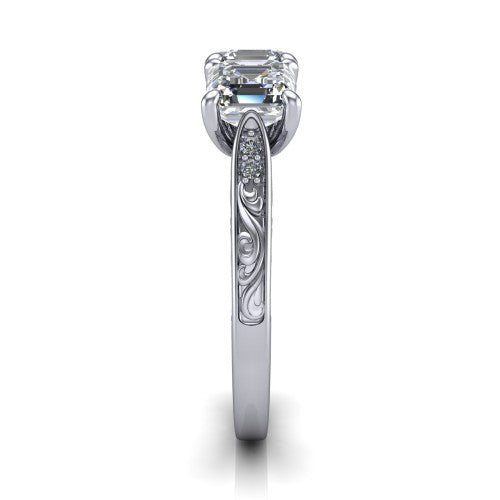 Navy square emerald three stone engagement ring in Platinum, side profile showing the vintage engraved filigree band and the raised three-stone setting