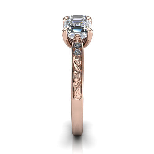 Navy square emerald three stone engagement ring in 14K Rose Gold, side profile showing the vintage engraved filigree band and the raised three-stone setting