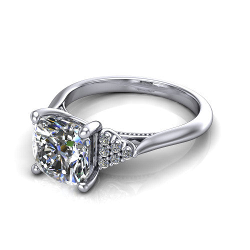 Raya cushion three stone engagement ring in 18K White Gold, three-quarter perspective showing the center stone flanked by a trio diamond cluster on each shoulder above a slim milgrain band