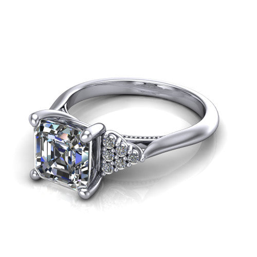 Raya square emerald three stone engagement ring in 18K White Gold, three-quarter perspective showing the center stone flanked by a trio diamond cluster on each shoulder above a slim milgrain band