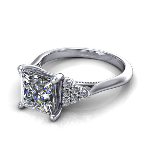 Raya princess three stone engagement ring in 14K White Gold, three-quarter perspective showing the center stone flanked by a trio diamond cluster on each shoulder above a slim milgrain band