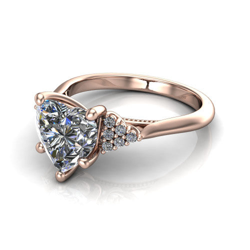 Raya heart three stone engagement ring in 18K Rose Gold, three-quarter perspective showing the center stone flanked by a trio diamond cluster on each shoulder above a slim milgrain band