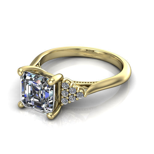 Raya square emerald three stone engagement ring in 18K Yellow Gold, three-quarter perspective showing the center stone flanked by a trio diamond cluster on each shoulder above a slim milgrain band