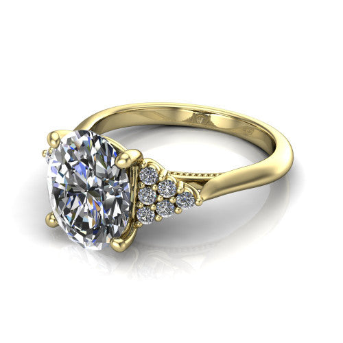 Raya oval three stone engagement ring in 14K Yellow Gold, three-quarter perspective showing the center stone flanked by a trio diamond cluster on each shoulder above a slim milgrain band