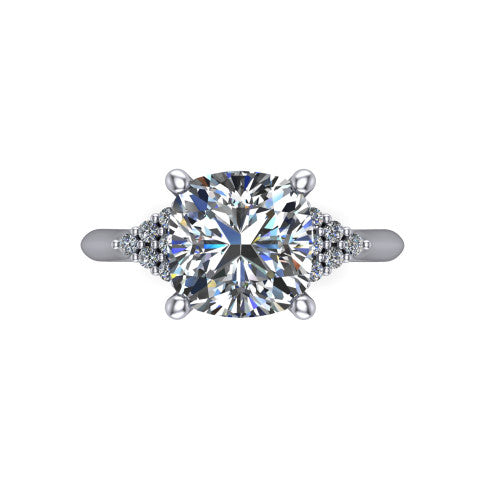 Raya cushion three stone engagement ring in 14K White Gold, top-down view showing the round center with graduated three-stone clusters to each side from above