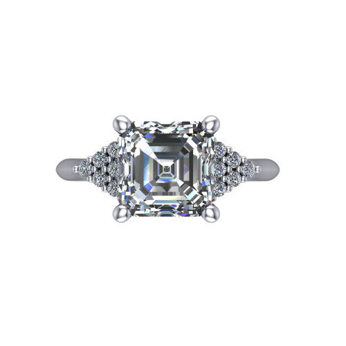 Raya square emerald three stone engagement ring in 14K White Gold, top-down view showing the round center with graduated three-stone clusters to each side from above