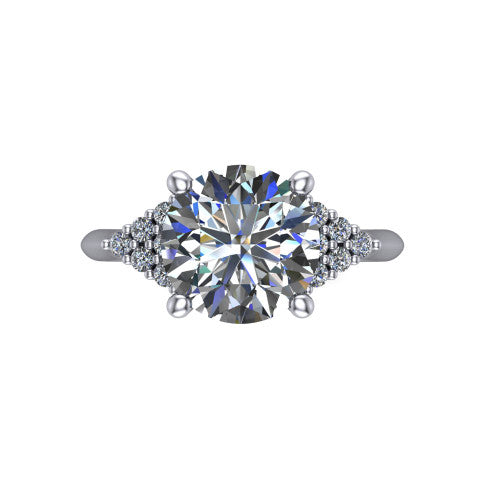 Raya round three stone engagement ring in 18K White Gold, top-down view showing the round center with graduated three-stone clusters to each side from above