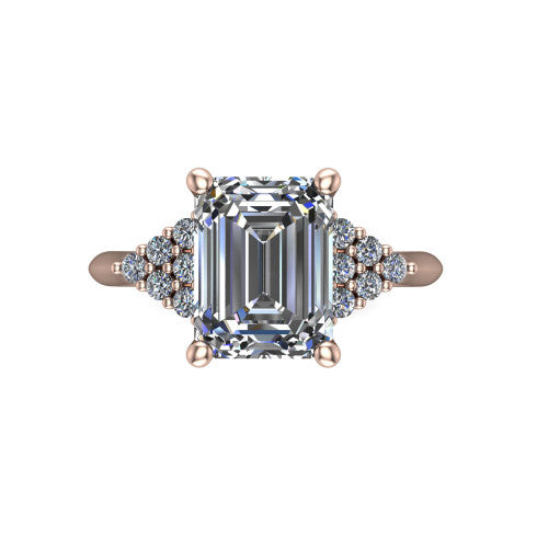 Raya emerald three stone engagement ring in 18K Rose Gold, top-down view showing the round center with graduated three-stone clusters to each side from above