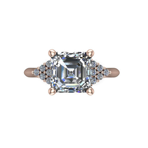 Raya square emerald three stone engagement ring in 18K Rose Gold, top-down view showing the round center with graduated three-stone clusters to each side from above