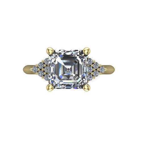 Raya square emerald three stone engagement ring in 14K Yellow Gold, top-down view showing the round center with graduated three-stone clusters to each side from above