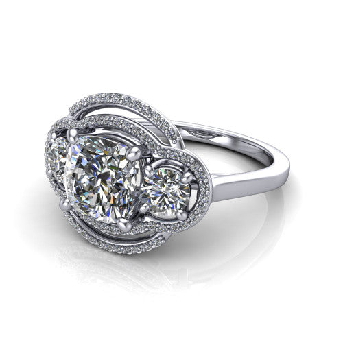 Elle cushion three stone halo engagement ring in Platinum, three-quarter perspective showing the center stone flanked by two side stones in an interlocking double pav&eacute; halo above a tapered band