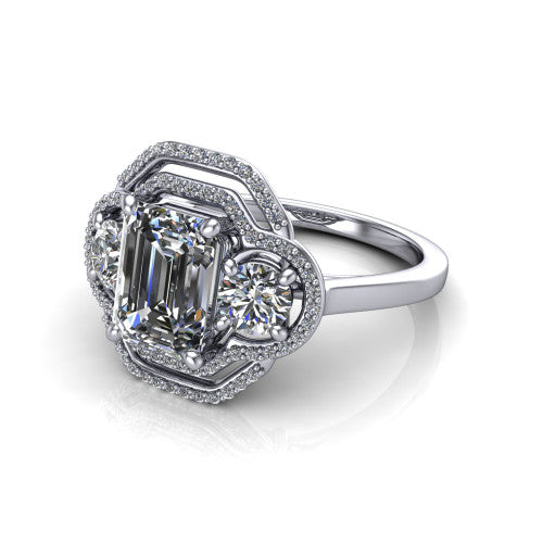 Elle emerald three stone halo engagement ring in Platinum, three-quarter perspective showing the center stone flanked by two side stones in an interlocking double pav&eacute; halo above a tapered band