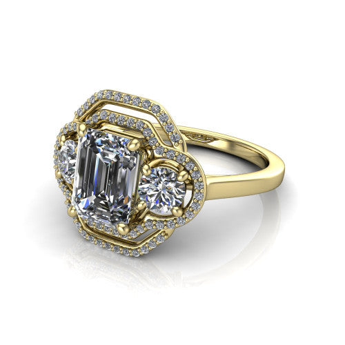 Elle emerald three stone halo engagement ring in 18K Yellow Gold, three-quarter perspective showing the center stone flanked by two side stones in an interlocking double pav&eacute; halo above a tapered band