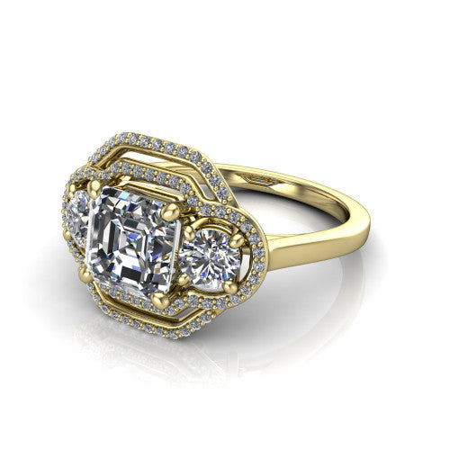 Elle square emerald three stone halo engagement ring in 18K Yellow Gold, three-quarter perspective showing the center stone flanked by two side stones in an interlocking double pav&eacute; halo above a tapered band