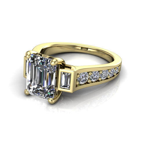 Estella emerald three stone engagement ring in 18K Yellow Gold, three-quarter perspective showing the center diamond between two tapered baguette side stones above a pav&eacute; band