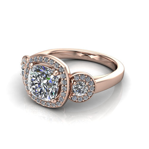 Wrenley cushion three stone engagement ring in 14K Rose Gold, three-quarter perspective showing the haloed center between two haloed round side stones on a polished band